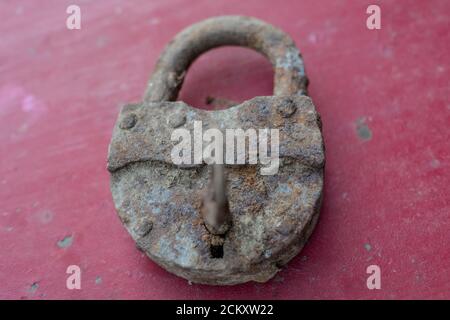Old metal rusty lock on a burgundy background close-up. Stock Photo