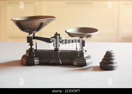 Old obsolete manual weighing scales and a pile of weights Stock Photo