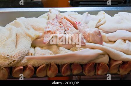 Raw pork feet and meat, stomach and tripe, used to cook menudo, displayed for sale on a counter in market in Latin America Stock Photo