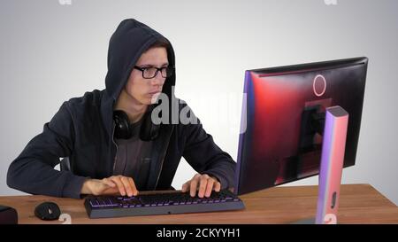 Hacker in glasses breaking code on gradient background. Stock Photo