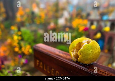 A fruit offering is seen placed on a wooden cross amongst the decorated graves at a cemetery during the Day of the Dead celebrations in Ayutla, Mexico. Stock Photo