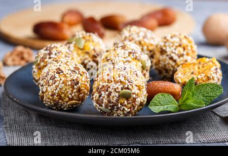 Energy ball cakes with dried apricots, sesame, linen, walnuts and dates with green mint leaves on a blue ceramic plate. side view, close up, macro, se Stock Photo