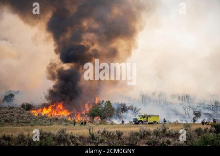 Firefighters watch the intense flames at the Pine Gulch Fire on the Western Slope August 2, 2020 near Grand Junction, Colorado. The wildfire is the largest in the history of Colorado destroying tens of thousands of ranch and wildlife habitats. Stock Photo