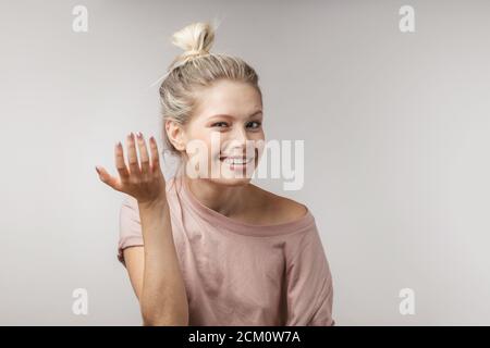 Studio portrait of attractive surprised astonished blonde woman with hair bun, looking at camera in full disbelief, having shocked expression on her f Stock Photo