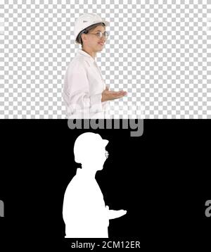 Young scientist in lab coat and hardhat walking and saying somet Stock Photo