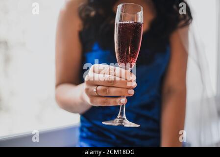bride dressed in blue satin suede pajamas holds a glass with red champagne Stock Photo
