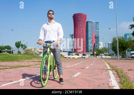 Young bearded man with sunglasses standing with bike outdoors Stock Photo
