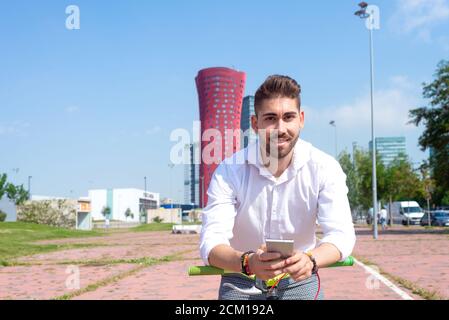 Outdoor portrait of handsome young man with mobile phone and fixed gear bicycle in the street. Stock Photo