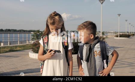 School friends boy and girl walking and looking into smartphone. Stock Photo