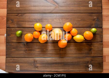 Creative flat layout of fruit, top view. Whole oranges, lemons, grapefruits, limes, isolated on dark wooden background. Stock Photo