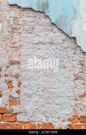 Old rough exposed red brick wall with plaster and paint falling off Stock Photo