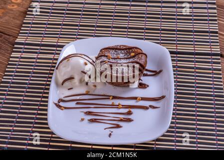 Concept: restaurant menus, healthy eating, homemade, gourmands, gluttony. White plate with chocolate fondant and ice cream on a messy vintage wooden b Stock Photo