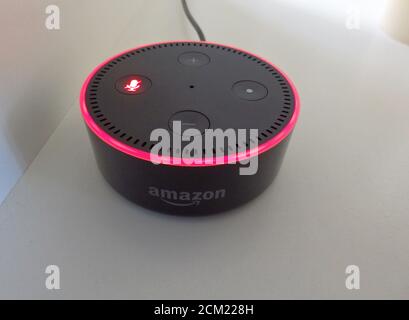 An Amazon Echo Dot is red due to the microphone being switched off. Stock Photo