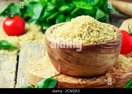 Bulgur in bowl, old wooden background, selective focus Stock Photo