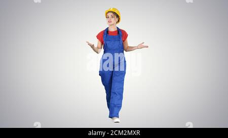 Cheerful female construction worker talking to camera on gradien Stock Photo
