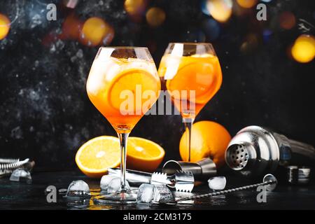 Aperol spritz cocktail in big wine glass with orange and ice, summer alcoholic cold drink, dark bar counter with steel bar tools, copy space Stock Photo