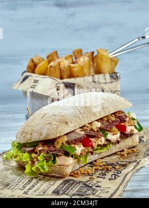 Philly Steak Sandwich. Classic American sandwich with a twist. Ciabatta bread-roll filled with rump steak slices on green salad leaves, red and green Stock Photo
