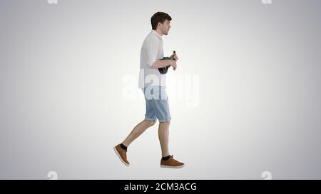 Young man playing ukulele while walking on gradient background. Stock Photo