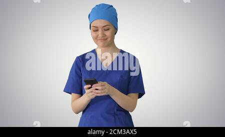 Female doctor or nurse in blue uniform using her phone as she wa Stock Photo