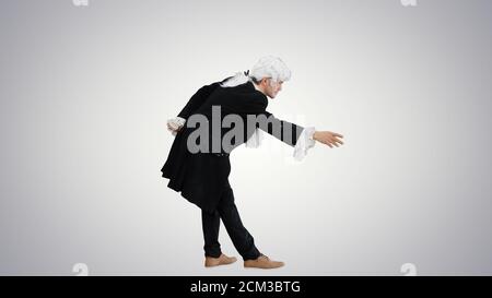 Man dressed as Mozart greeting someone on gradient background. Stock Photo
