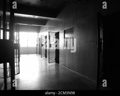 Black and white view of rundown jail cell block in an unused government owned facility. Stock Photo