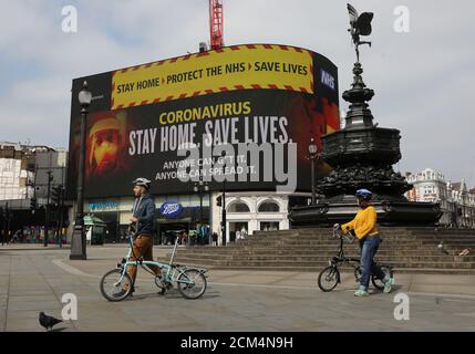 Two cyclists pass by a message of support for NHS workers on a screen in Piccadilly Circus, as the spread of the coronavirus disease (COVID-19) continues, London, Britain, April 18, 2020. REUTERS/Simon Dawson
