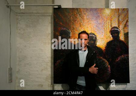Street artist James Cochran, also known as Jimmy C, poses next to his spray painted picture 'Riot Police' at the Pure Evil Gallery in London October 10, 2013. The paintings were originally inspired by the London riots in 2011. REUTERS/Stefan Wermuth (BRITAIN - Tags: ENTERTAINMENT SOCIETY)
