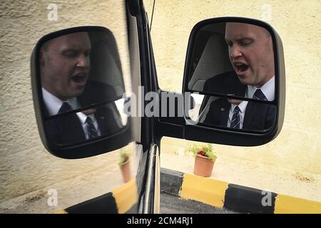 A U.S. official is reflected on the side mirror of a press pool van while he yawns as the van was held for a time at the main entrance to King Abdullah II's palace in Amman, October 24, 2015. REUTERS/Carlo Allegri