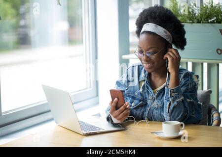 Keeping business on top with digital technologies. Cheerful young African american business lady, talking on smartphone and looking at digital tablet Stock Photo