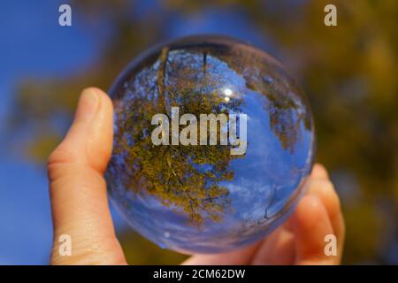 Reflection of Fall Trees and blue sky during the golden hour in a glass ball Stock Photo