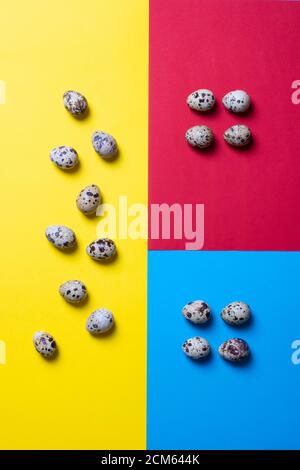 Quail eggs creative concept. Raw small eggs on a yellow, blue and red background. Top view, flatlay food Stock Photo