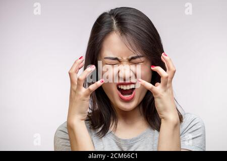 Isolated studio shot of furious Asian young wife screams desperately, being angry, irritated and aggressive while quarelling with her husband. Negativ Stock Photo