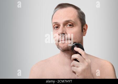 handsome man shaves with an electric razor, 35-40 years old Stock Photo