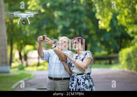 Happy elderly couple on a walk. Elderly husband and wife with a drone. Loving spouses in adulthood. Stock Photo