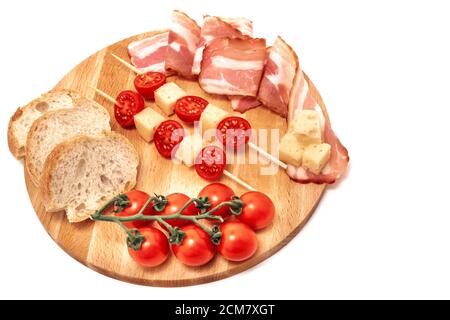 composition of cheese tomatoes bacon and bread on wooden board, isolated white background Stock Photo