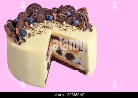 beautiful cake on a purple, decorated with blueberries and cookies, triangular section shown isolated on purple background, close-up Stock Photo