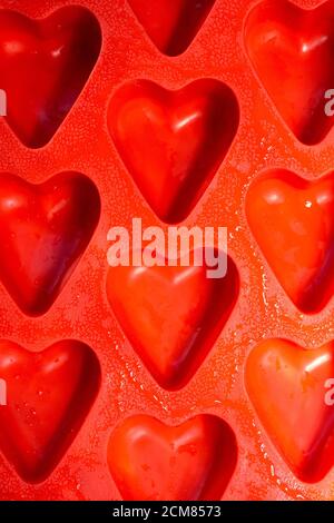 red hearts vertical background, silicone ice molds in the form of hearts. Bright red hearts abstract background Stock Photo