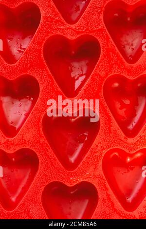 red hearts background, silicone ice molds in the form of hearts. Bright red hearts abstract background Stock Photo