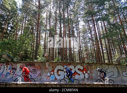 Downhill bikers Kemal Mulic (L-R), Kamer Kolar and Tarik Hadzic train on the disused bobsled track from the 1984 Sarajevo Winter Olympics on Trebevic mountain near Sarajevo, Bosnia and Herzegovina, August 8, 2015. Abandoned and left to crumble into oblivion, most of the 1984 Winter Olympic venues in Bosnia's capital Sarajevo have been reduced to rubble by neglect as much as the 1990s conflict that tore apart the former Yugoslavia. The bobsled and luge track at Mount Trebevic, the Mount Igman ski jumping course and accompanying infrastructure are now decomposing into obscurity. The bobsled and 