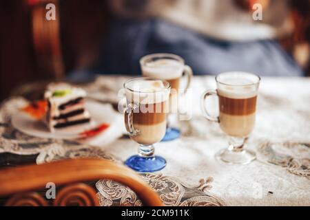 Glass mugs with delicious coffee on the table, sweet pastries, coffee break, family gatherings Stock Photo