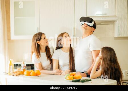 Father, wife and daughters in virtual reality glasses having fun at home Stock Photo