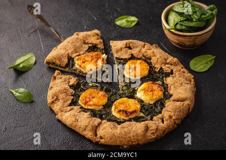 Rustic spinach and goat cheese galette on black background. Stock Photo