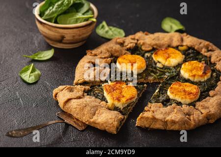 Rustic spinach and goat cheese galette on black background. Stock Photo