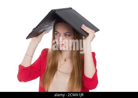 A young business office woman in a red suit, fooling around, holding an open laptop on his head, a background isolated in white Stock Photo