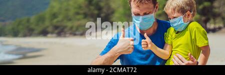 Banner Father squatting holding son playing fists with thumbs up, wearing face blue mask protect coronavirus walking nature sand sea beach near forest Stock Photo