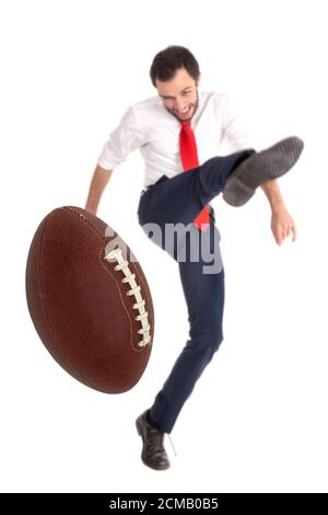 Businessman kicking  aa American football ball or rugby ball isolated in white Stock Photo