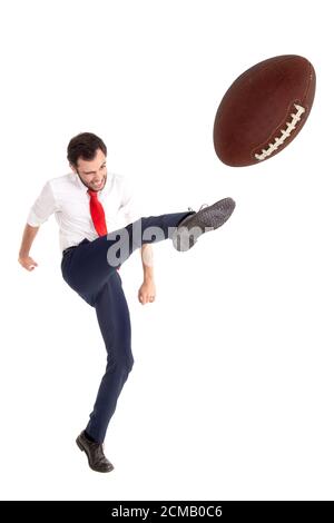 Businessman kicking  aa American football ball or rugby ball isolated in white Stock Photo