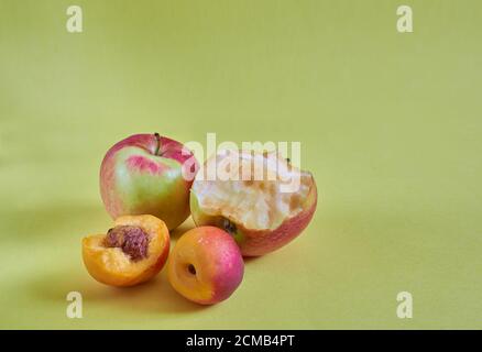 Whole and nibbled apples and nectarines lie on a colored background. Close up Stock Photo