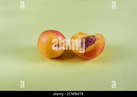 Whole and bitten nectarines lie on a colored background. Close up Stock Photo