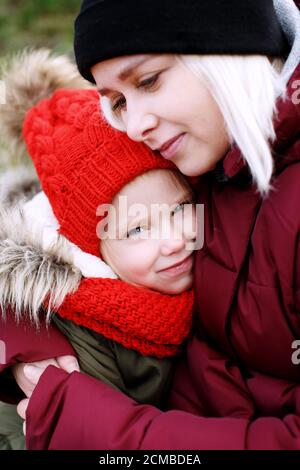 Young pretty mother holding hugging her cute little preschool daughter smiling, close up portrait concept of bonding